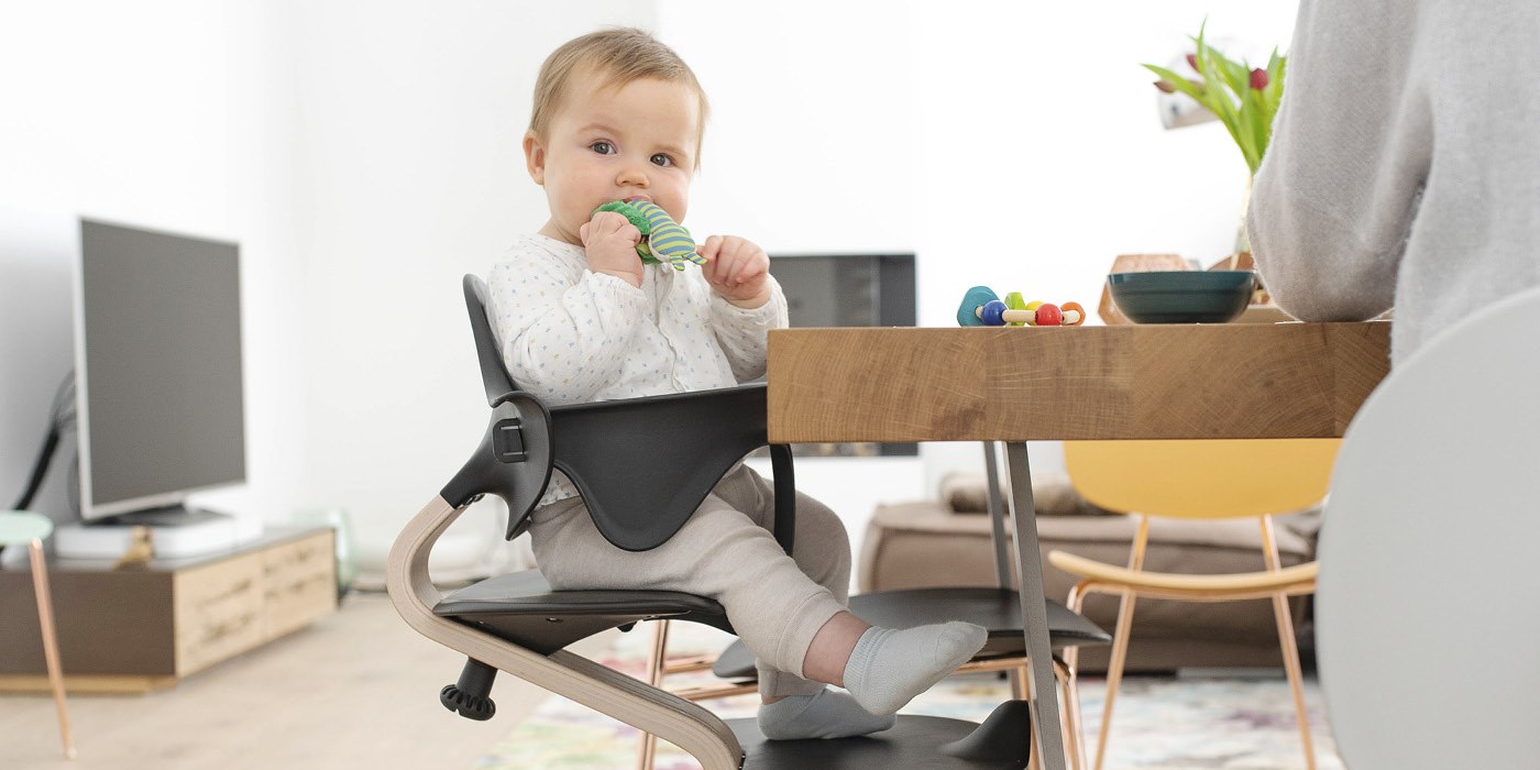 A baby seated in a Stokke Nomi chair with the Nomi Baby Set