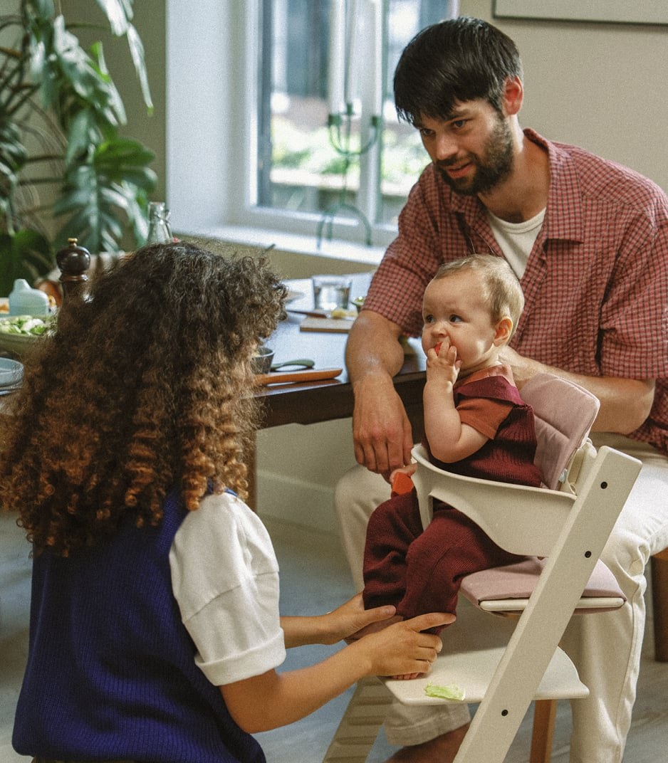 A parent feeding a baby who sits in a Tripp Trapp with the Baby Set 2 and a Stokke Tray